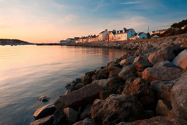 View of sea wall and houses of seaside village overlooking harbour at sunset, Instow, North Devon, England, september