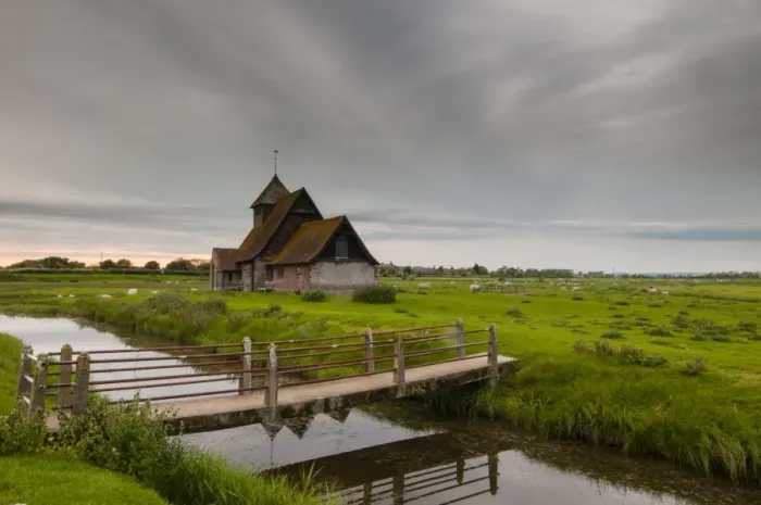 Framed Print : View of sheep on grazing marsh with footbridge across flooded ditch and church in evening, St Framed Print : View of sheep on grazing marsh with footbridge across flooded ditch and church in evening, St
