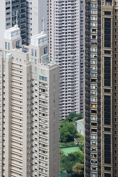 View of small garden and tennis court amongst skyscraper apartment blocks in densely populated area of city, Hong Kong