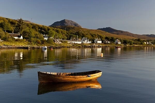 View of small wooden boat and village houses in bay, in morning sunlight, with Beinn Shiantaidh and Corra Bheinn