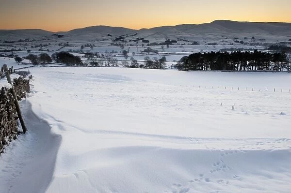 View of snow covered farmland in evening, overlooking Ravenstonedale area on northern fringe of Howgill Fells, Cumbria