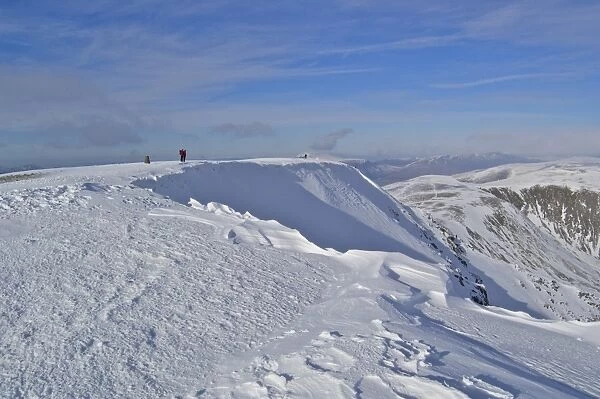 View of snow covered fell summit with walkers, Helvellyn, Eastern Fells, Lake District N. P. Cumbria, England, february