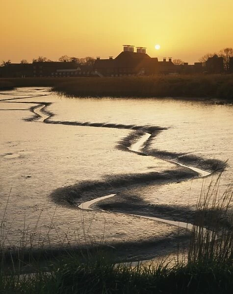 View of tidal river at low tide and arts complex on riverbank at sunset, Snape Maltings, River Alde, Snape, Suffolk