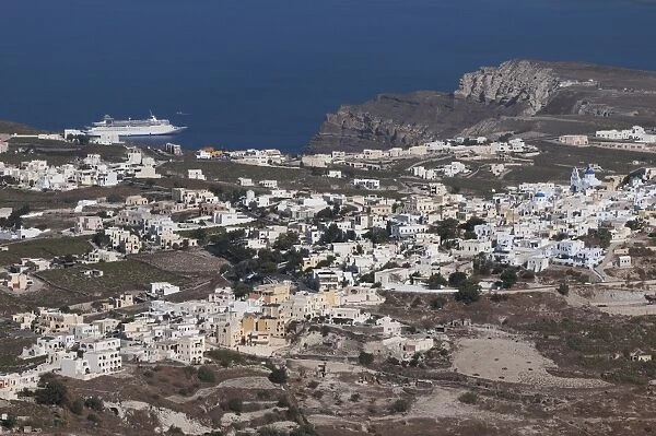 View of town, volcanic coastline and cruise ship at sea, Pirgos, Santorini, Cyclades, Aegean Sea, Greece, September