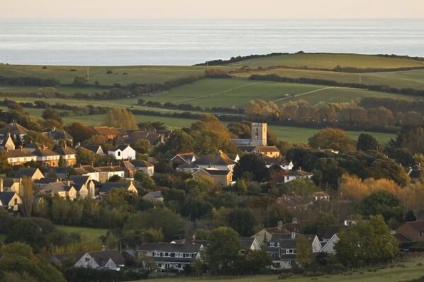 View of village, church, farmland and sea in distance, Preston, Dorset, England, october