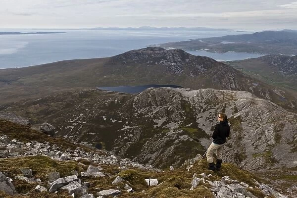Walker on mountain peak, view north across Loch Tarbert, northern part of Colonsay visible in northwest