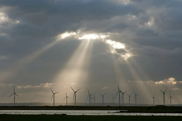 Wind turbines on windfarm with sunbeams through clouds at sunset, Little Cheyne Court, Romney Marsh, Kent, England