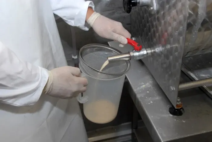 Framed Print : Worker extracting whey from churn, making organically made butter from unpasteurized milk, on organic dairy farm Framed Print : Worker extracting whey from churn, making organically made butter from unpasteurized milk, on organic dairy farm