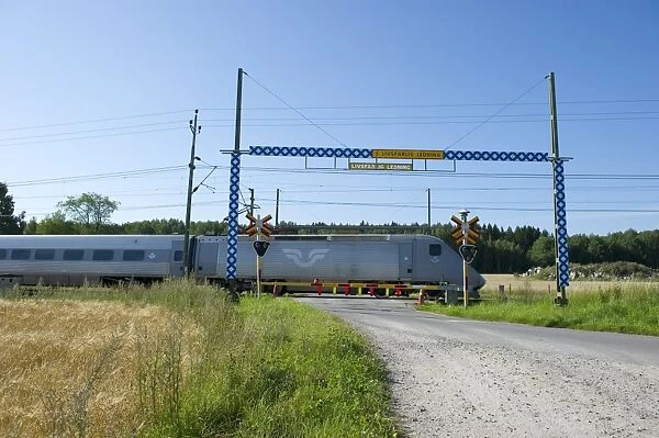 X2000-train passing rural crossing, Sodermanland, Sweden, august