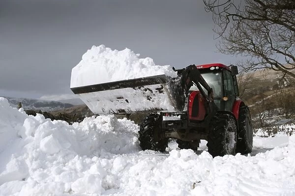 Zetor tractor with loader clearing snow from blocked rural road after snowstorm, Cumbria, England, March