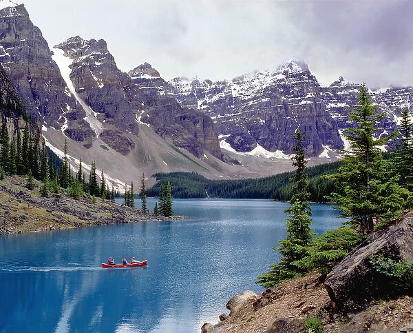 Canada, Alberta, Moraine Lake. A canoe glides across beautiful Moraine Lake in the