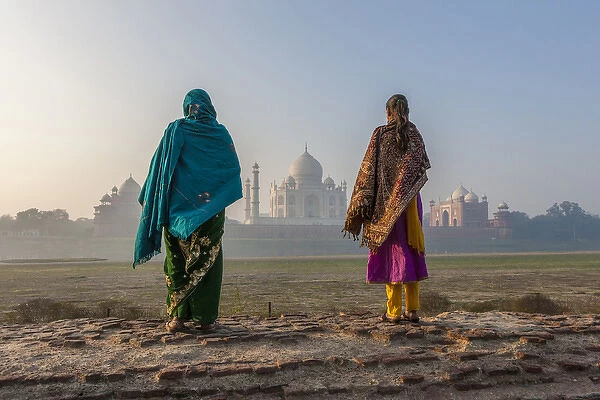 Women walking Mehtab Bagh, Moon Garden across from Taj Mahal in morning mist. Agra. India