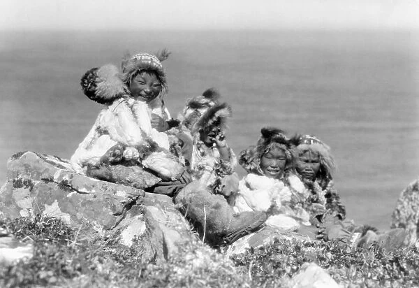 ALASKA: ESKIMOS, c1929. Four Eskimo children sitting on the edge of cliff, dressed