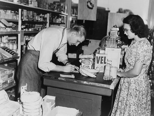 BANANA INDUSTRY, c1948. At a grocery store, a clerk writes up a customers grocery bill