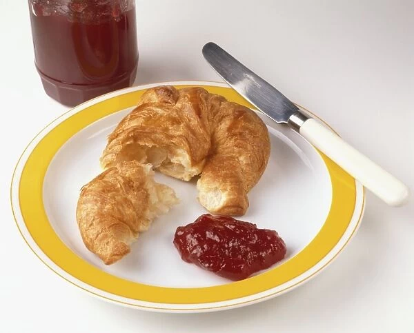 Croissant and jam on a plate together with a knife