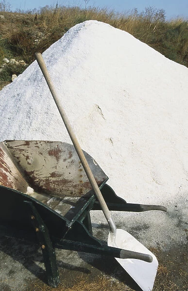 France, Sel de Guerande, pile of sea salt and shovel leaning on wheelbarrow