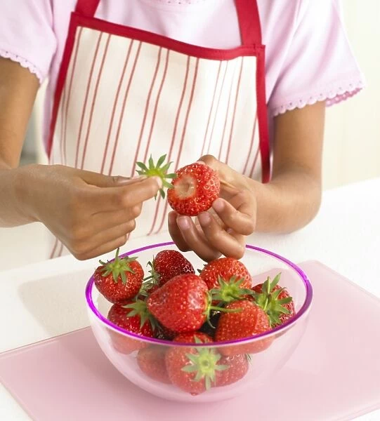 Girl plucking stems from strawberries