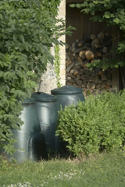 Three green plastic compost bins by wall