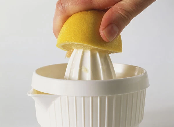 Half a lemon being squeezed over a lemon juicer