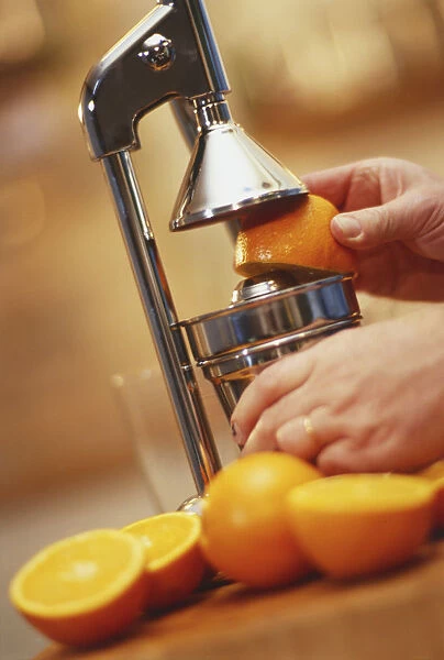 Hand holding half an orange in a juicer