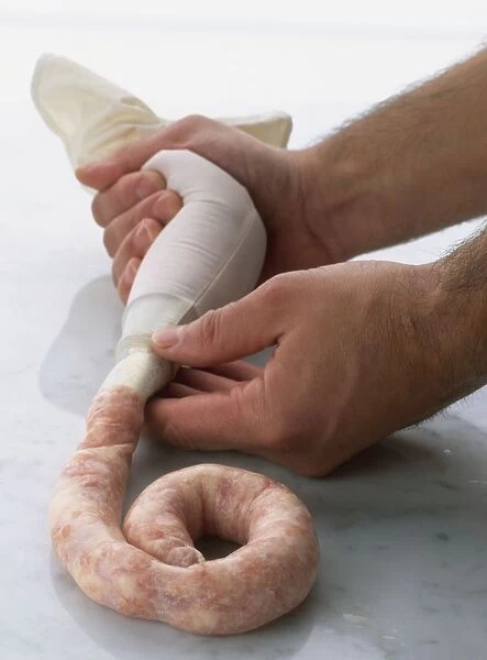 Hands squeezing sausage mixture from piping bag