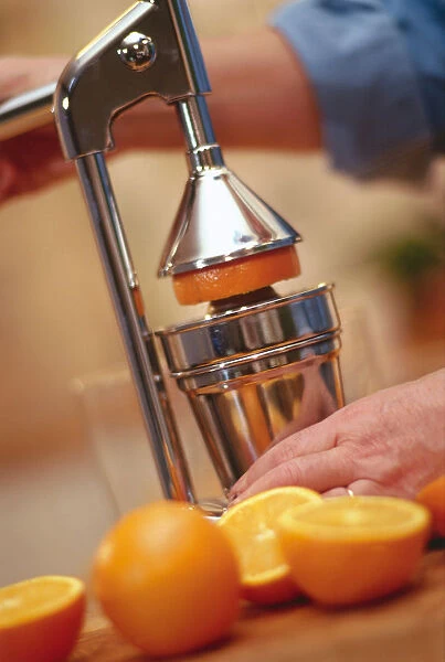 Man juicing oranges in a silver juicer