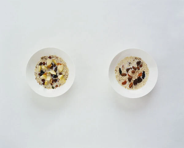 Muesli in white bowls with dried fruit and nuts