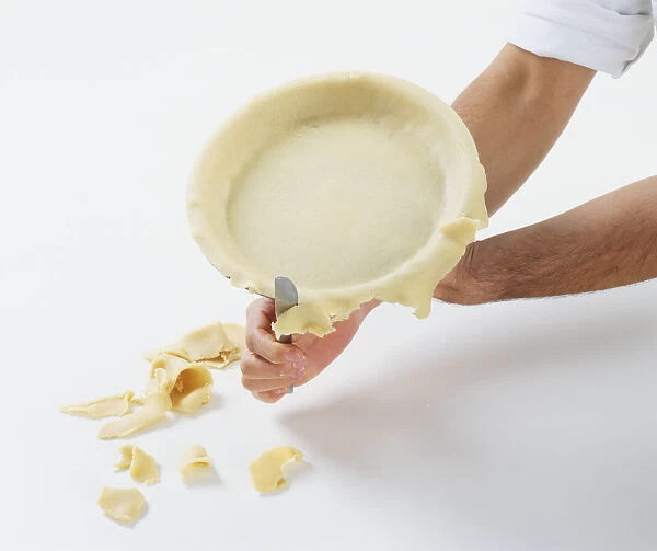 Person trimming excess pastry from pie dish