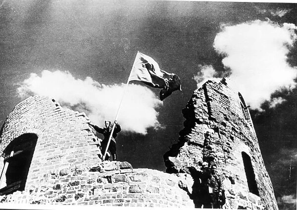 Once more the red flag of the ussr flutters in the wind as a red army fighter unfurls it over the old kaunas fortress