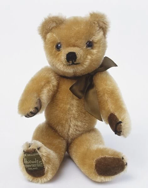 Sitting teddy bear with silky brown bow tie, front view