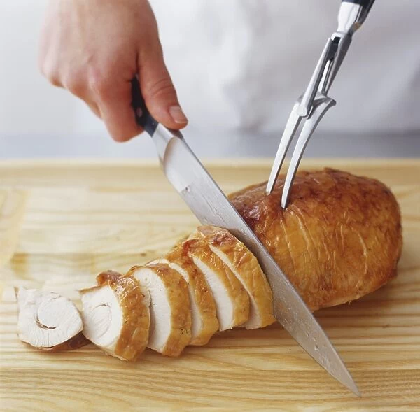 Turkey breast being sliced with knife and carving fork, high angle view