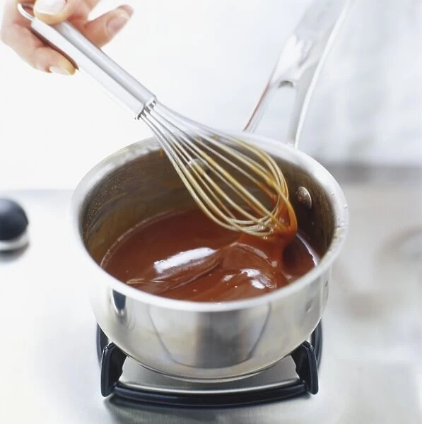 Using a hand whisk to stir caramel sauce