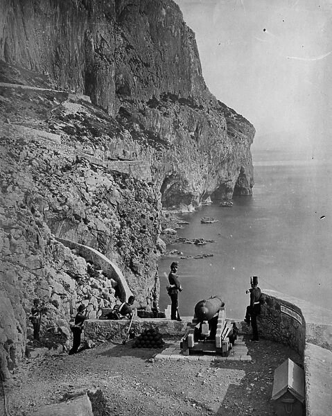 Gibraltar. 1862: Soldiers stand guard by a cannon overlooking the sea on
