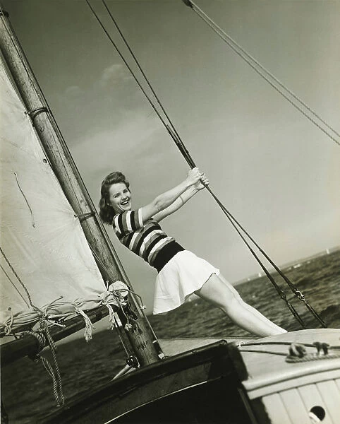 Young woman holding rigging on yacht, (B&W)