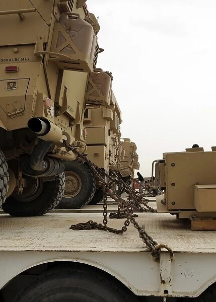 Military vehicles are locked down on semi trucks