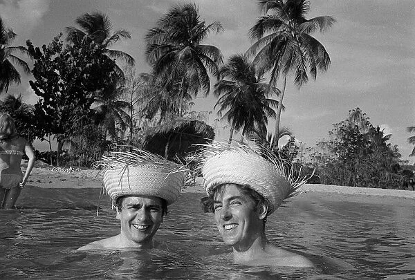 Peter Cook and Dudley Moore on holiday in Bahamas 1966 wearing straw hats inthe sea