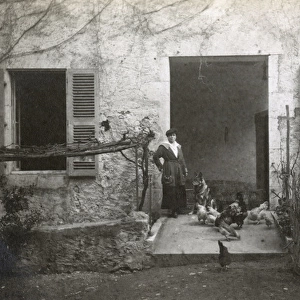 Woman with a dog and chickens in a garden, France