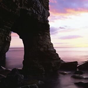 Dawn view over North Sea from beach at Marsden Bay, showing natural rock arch in Marsden Rock