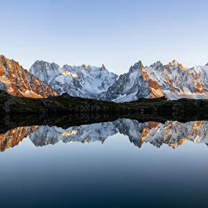 Panoramic of Mont Blanc Massif covered with snow reflected in Lacs de Cheserys at sunset
