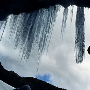 Climber abseiling over the mouth of an ice cave, Lewis Glacier