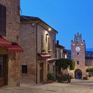 The clock tower of the medieval village of Gradara before sunrise with the hills in