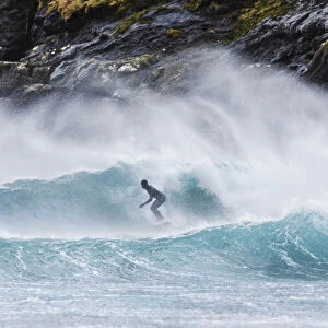 A guy surfing along the coast in front of Tjornuvik. Streymoy, Faroe Islands