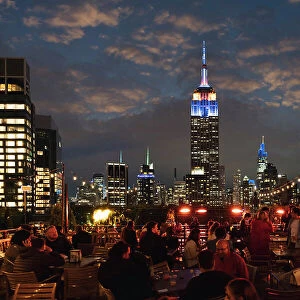 Manhattan rooftop, people having fun wit skyline on background at night, New York City, USA