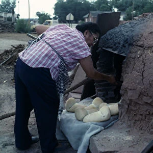 USA, New Mexico, Zuni Zuni Pueblo Native American Indian woman making bread in a Horno