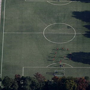 An aerial view shows soccer players standing on a field on a sunny autumn day in