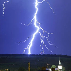 A fork of lightning strikes a mountain during a thunderstorm near the town of Barr south