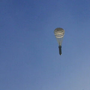 A missile hangs on a parachute while falling over the rebel-held besieged al-Qaterji