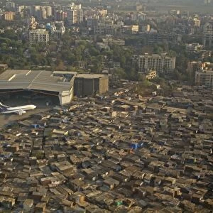 Aerial view of slum areas surrounded by luxury apartments, offices and airport, India, February