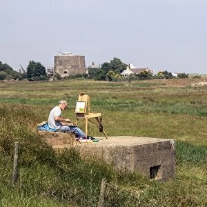 Artist sitting on World War 2 pill box looking over Oxley marsh at Shingle Street, Suffolk
