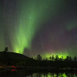 Aurora Borealis and stars over lake at night, Muonio, Lapland, Finland, September